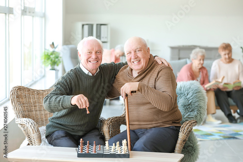 Fotografering Senior men playing chess in nursing home