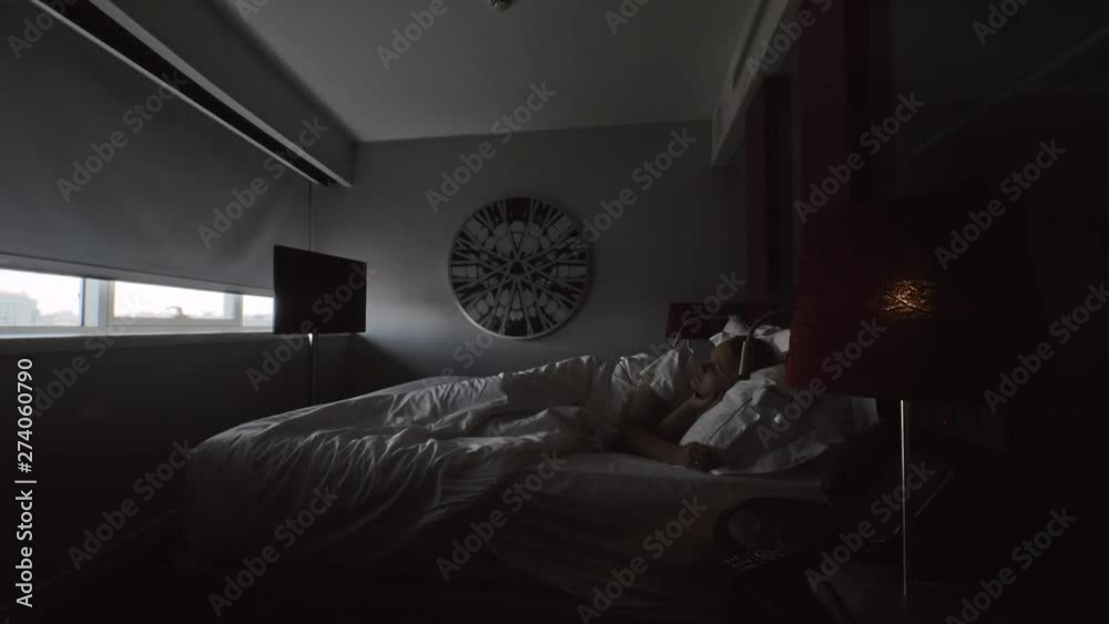 A young woman awakes in a bedroom when the window blind goes up automatically