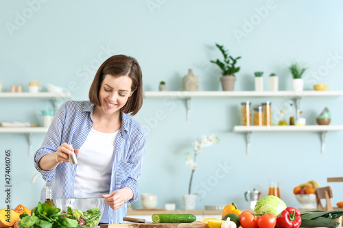 Young woman making salad in...