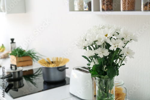 Vase with bouquet of flowers on counter in kitchen © Pixel-Shot