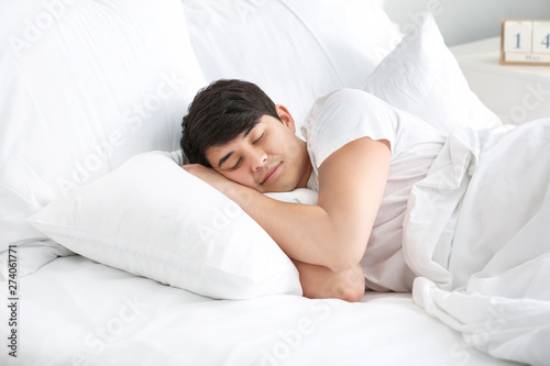 Handsome young man sleeping in bed