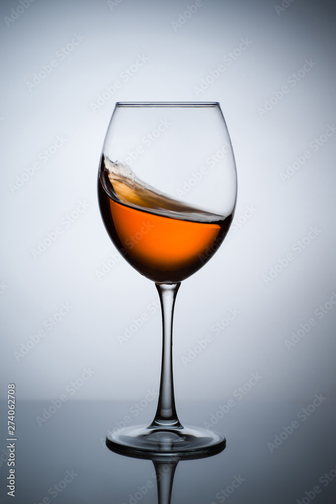 Amber wine. A splash of wine in a glass. Liquid in a glass. Traditional wine according to the ancient Georgian technology. Concept with a glass of wine. Copy space. Close up and vertical orientation.