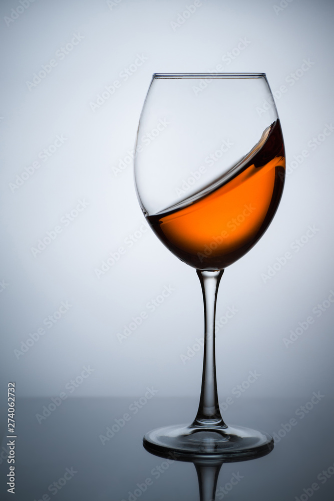 Amber wine. A splash of wine in a glass. Liquid in a glass. Traditional wine according to the ancient Georgian technology. Concept with a glass of wine. Copy space. Close up and vertical orientation. Amber wine. A splash of wine in a glass. Liquid in a glass. Traditional wine according to the ancient Georgian technology. Concept with a glass of wine. Copy space. Close up and vertical orientation.