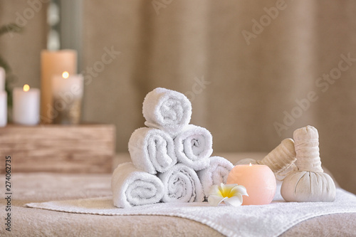 Rolled towels, herbal bags, candle and flower on table in spa salon
