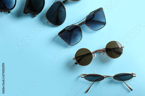 Different modern sunglasses on color background