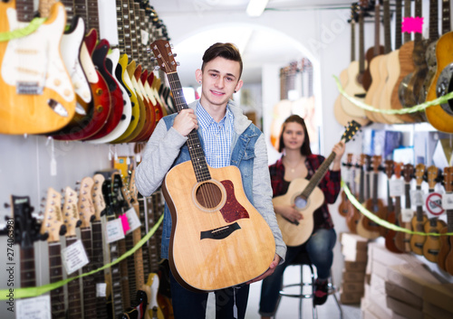 Teenagers examining guitars in shop