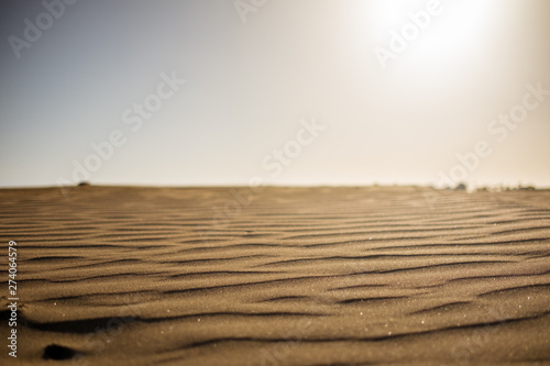 ground level view of desert sand at sunset with sun hitting hard from above giving a sense warm and hot wth nobody