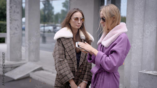 Two women standing outside in autumn looking stylish, two friends talking.