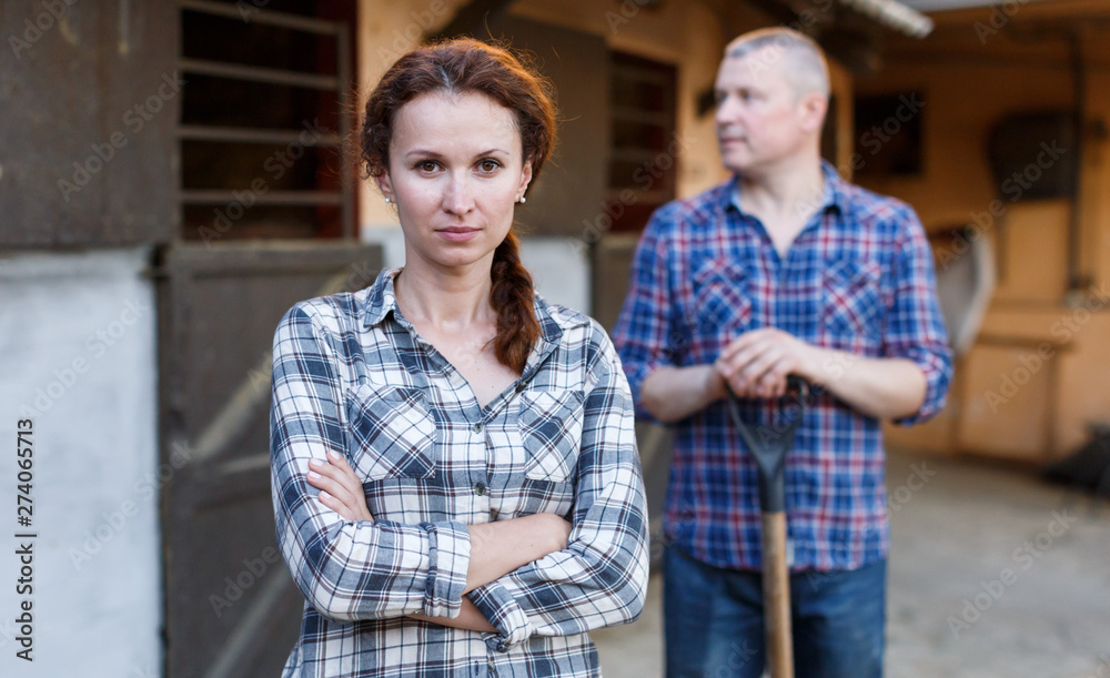 Mature couple standing with tools at farm with pet outdoor
