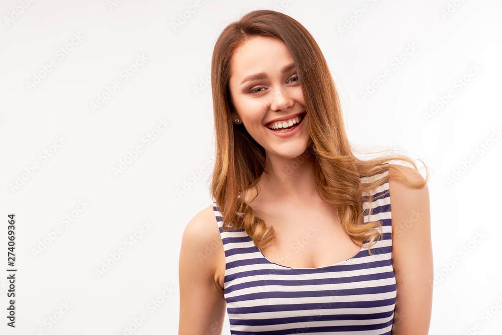 A long-haired girl in a striped t-shirt laughs happy and looks at the camera. Large Studio isolated portrait on a white background A long-haired girl in a striped t-shirt laughs happy and looks at the camera. Large Studio isolated portrait on a white background