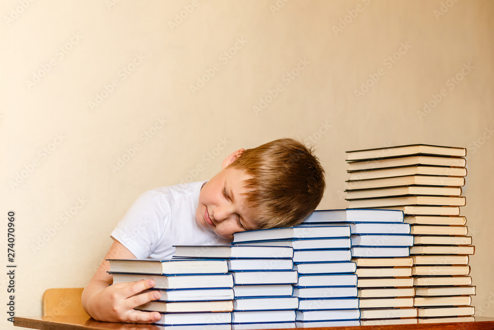 tired eight-year-old boy sleeping on books at the table. children and reading. tired eight-year-old boy sleeping on books at the table. children and reading.