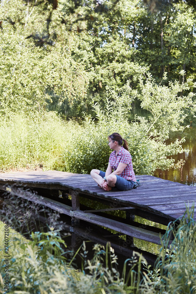 Woman sitting on a bridge over a lake during summer vacations