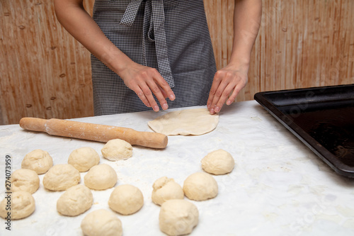 Girl rolls the dough in the kitchen