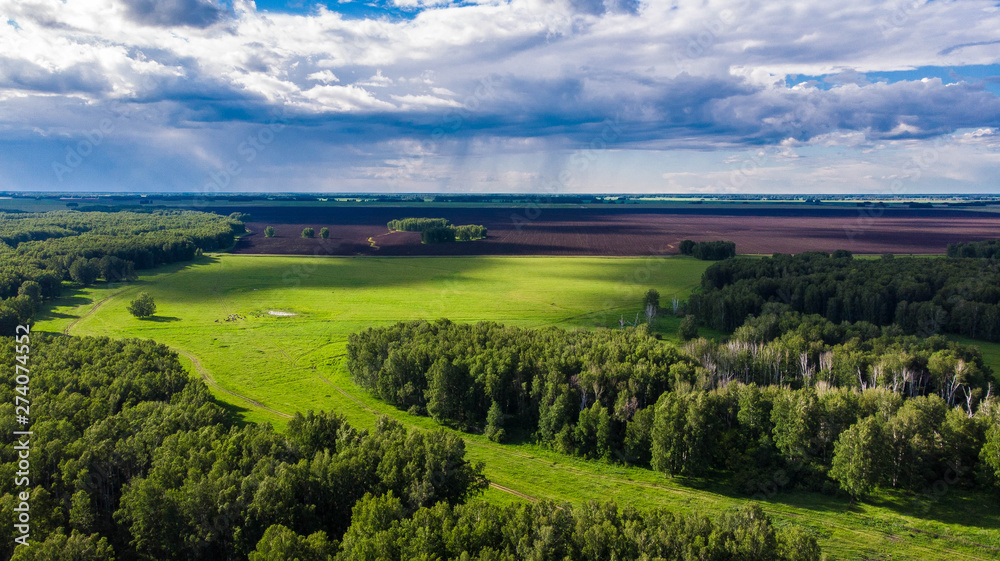 Obraz premium Aerial shot. Amazing green valley with oncoming thunderstorm clouds on bright summer day