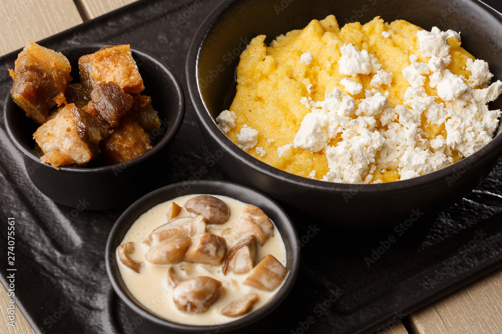 Typical Ukrainian dish polenta - Banosh with cheese and lard. Ukrainian cuisine. maize porridge with bacon, cracklings and cheese Corn porridge in plate on wooden background. Typical Ukrainian dish polenta - Banosh with cheese and lard. Ukrainian cuisine. maize porridge with bacon, cracklings and cheese Corn porridge in plate on wooden background.