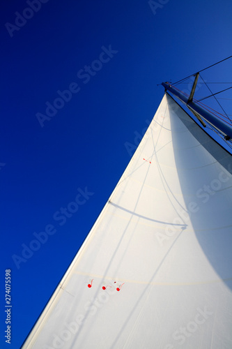 Looking up main sail of sailing yacht with wind direction indicators flapping in the breeze
