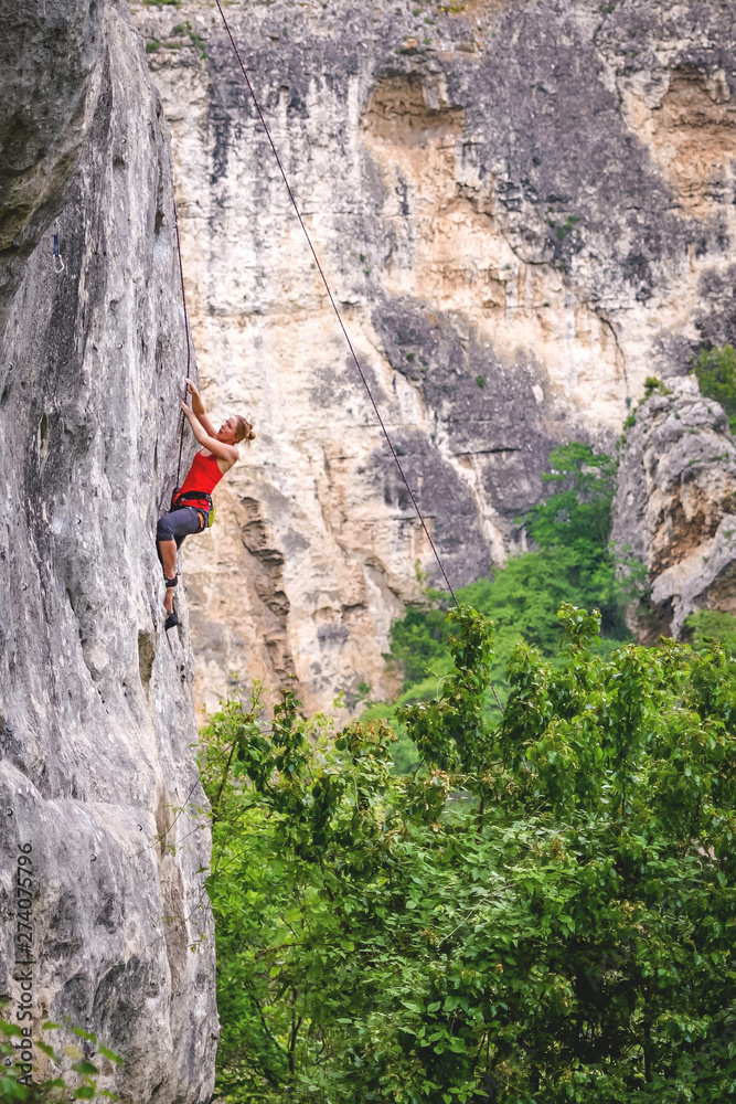 Woman climbs rock.
