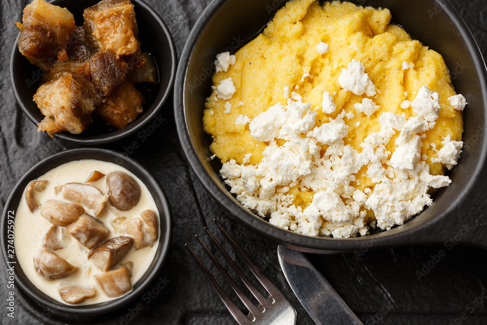 Typical Ukrainian dish polenta - Banosh with cheese and lard. Ukrainian cuisine. maize porridge with bacon, cracklings and cheese Corn porridge in plate on wooden background. Typical Ukrainian dish polenta - Banosh with cheese and lard. Ukrainian cuisine. maize porridge with bacon, cracklings and cheese Corn porridge in plate on wooden background.