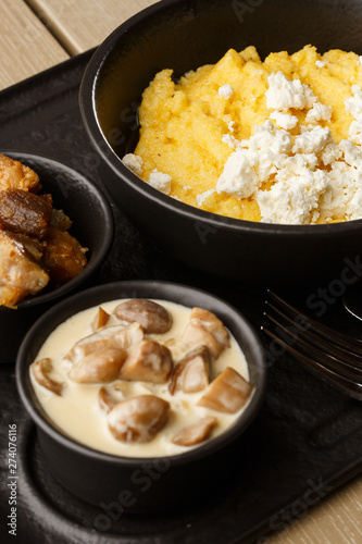 Typical Ukrainian dish polenta - Banosh with cheese and lard. Ukrainian cuisine. maize porridge with bacon, cracklings and cheese Corn porridge in plate on wooden background.
