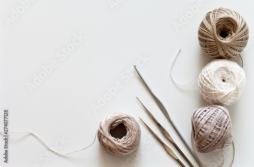 Needlework. Crochet hooks and balls of cotton yarn beige color on a white table. Тоp view, closeup, flat lay, copy space photo