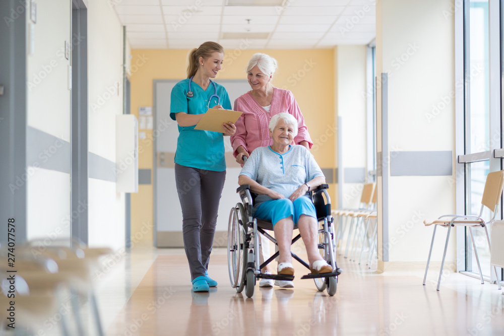 Elderly woman on wheelchair with her daughter and nurse Elderly woman on wheelchair with her daughter and nurse