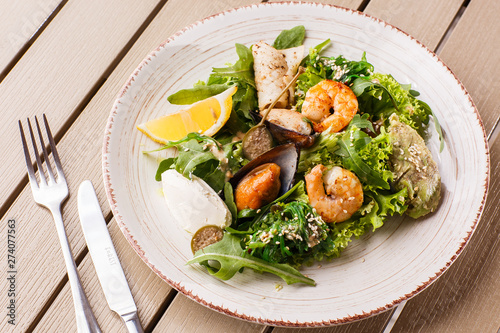 Healthy Salad. Recipe for fresh seafood. Grilled shrimps, mussels and squid, fresh salad lettuce and avocado puree. Healthy Eating. Wooden background