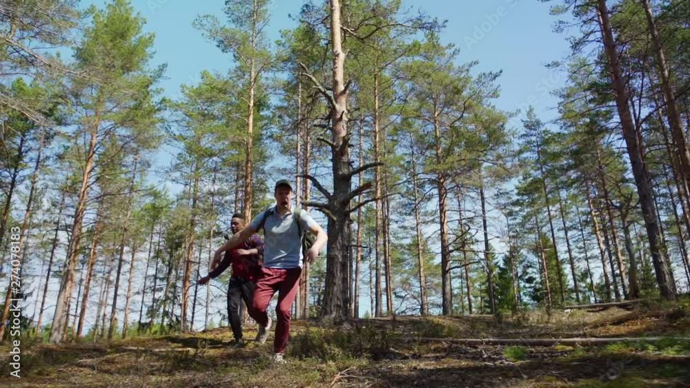 Two terribly scared young backpackers running through forest in slow motion and screaming awfully, low angle view Two terribly scared young backpackers running through forest in slow motion and screaming awfully, low angle view