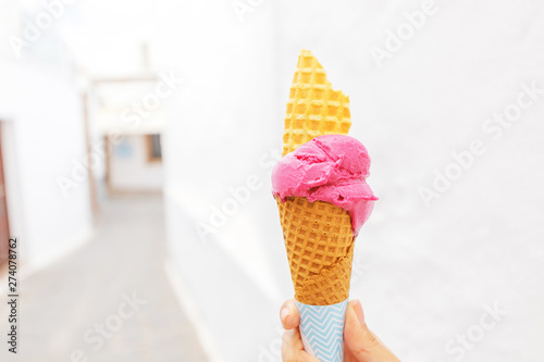 Ice cream cone in hand on a background of white street town. Travel deesert and diet concept photo