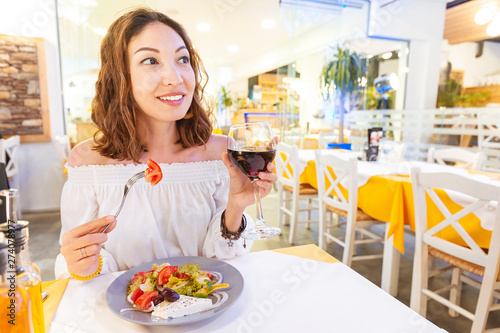 Young woman eating salad and drinking wine in restaurant © EdNurg