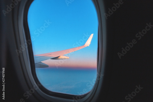 View from aircraft window on wing and pink colors of a majestic sunset