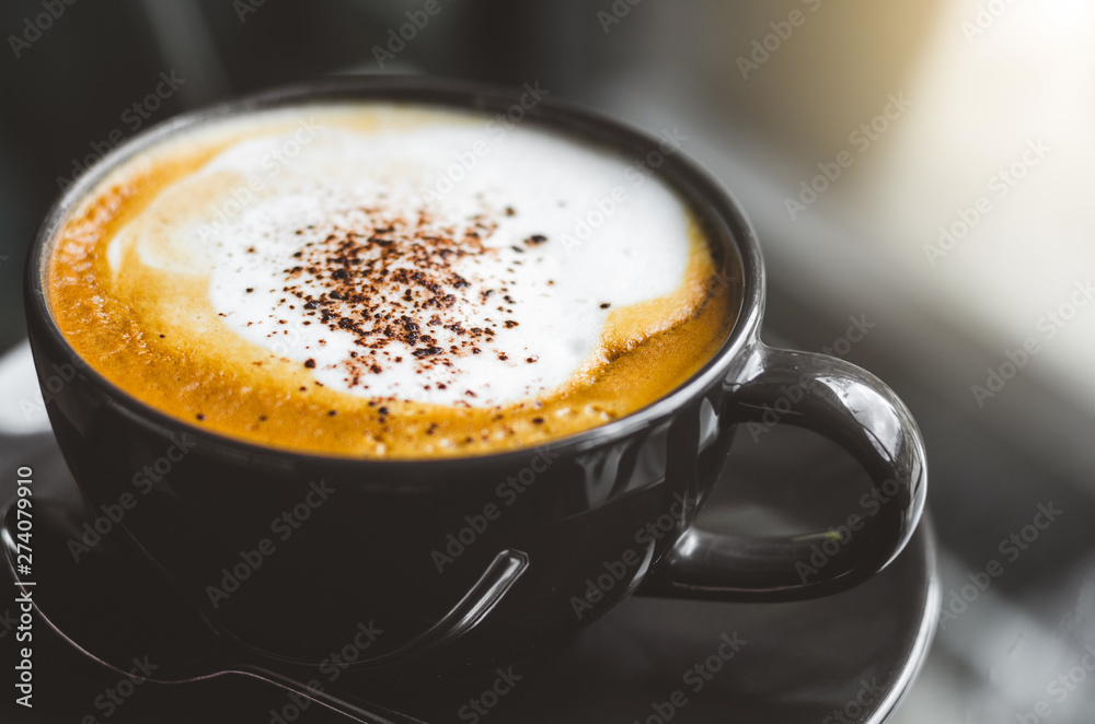 close up modern hot black coffee the cappuccino on dark background with coffee bubble foam pattern and texture in black cup looking and feel so delicious on glasses table in coffee shop. close up modern hot black coffee the cappuccino on dark background with coffee bubble foam pattern and texture in black cup looking and feel so delicious on glasses table in coffee shop.