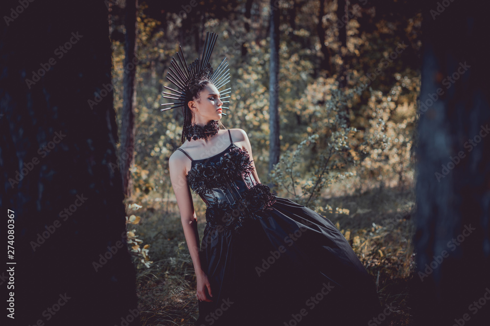 Naklejka premium selective focus of beautiful woman in black witch costume standing between trees