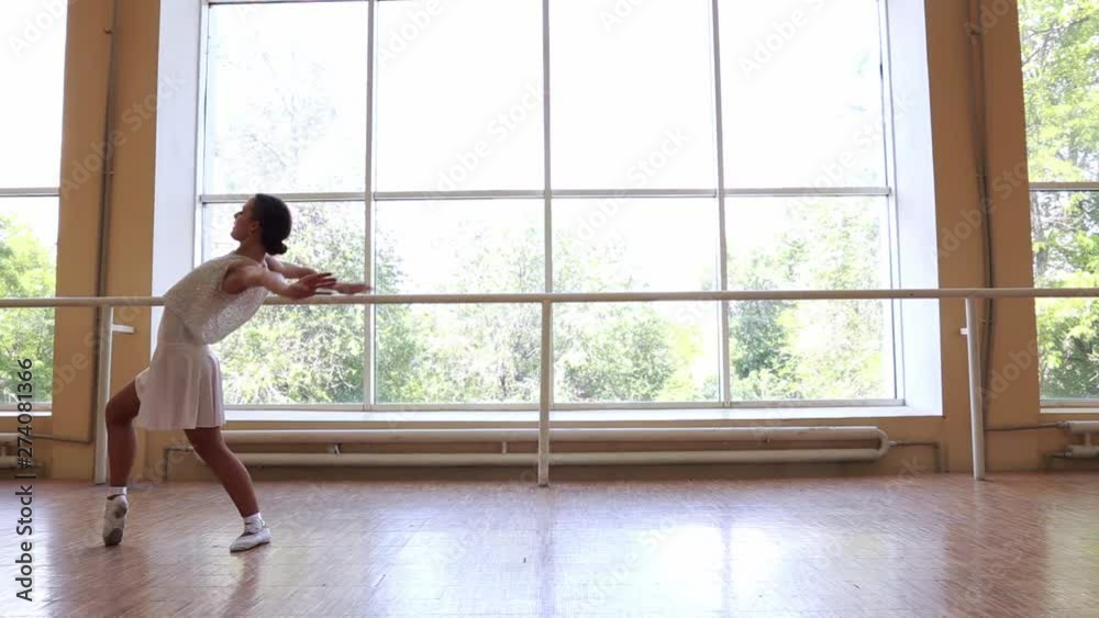 Young thin ballerina in white dress dancing near a big window. Young thin ballerina in white dress dancing near a big window.
