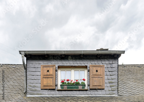 Slate roof with dormer window with two romantic windows and wooden shutters photo