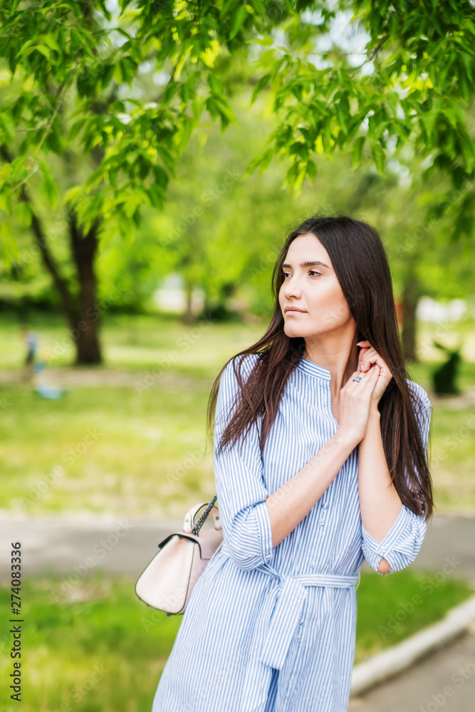 A girl of Asian appearance on a walk in a city park. Summer portrait of young Tatar on a background of green foliage A girl of Asian appearance on a walk in a city park. Summer portrait of young Tatar on a background of green foliage