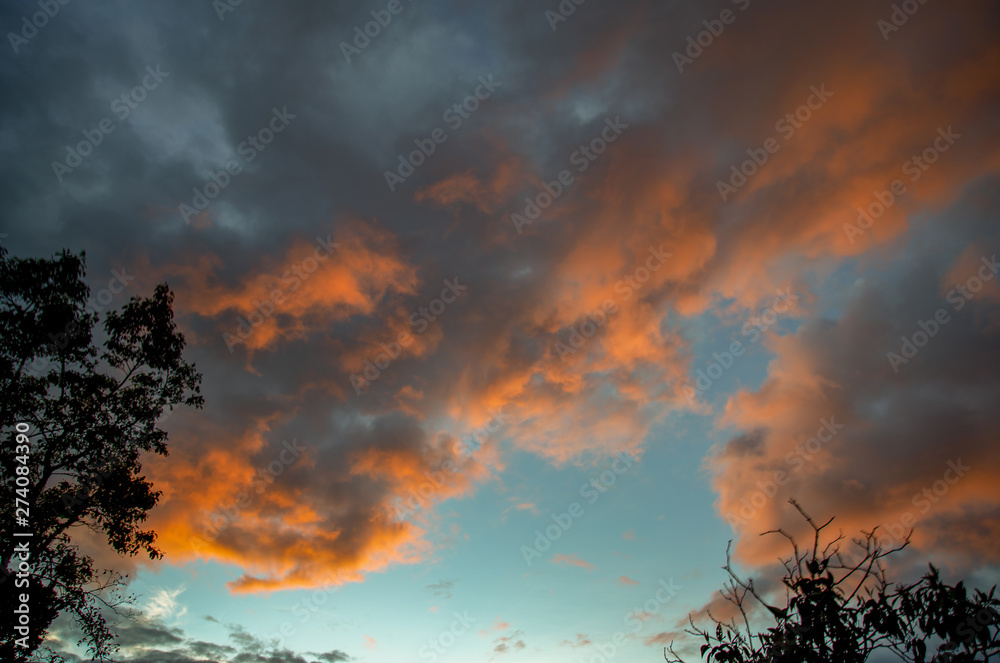 Fototapeta premium Multiple exposure of some clouds illuminated in yellow by the sunset light in the central Andean mountains of Colombia.
