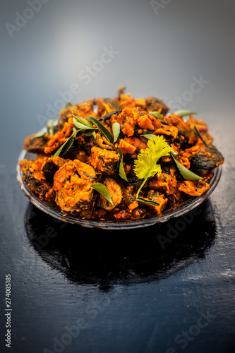 Famous Indian & Gujarati snack dish in a glass plate on wooden surface i.e. Patra or paatra consisting of mainly Colocasia esculenta or arbi ke pan or elephant ear leaves and spices.Vertical shot. photo