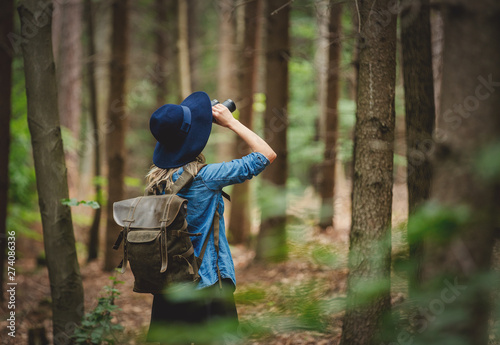 Young woman with binocular and backpack in a forest photo