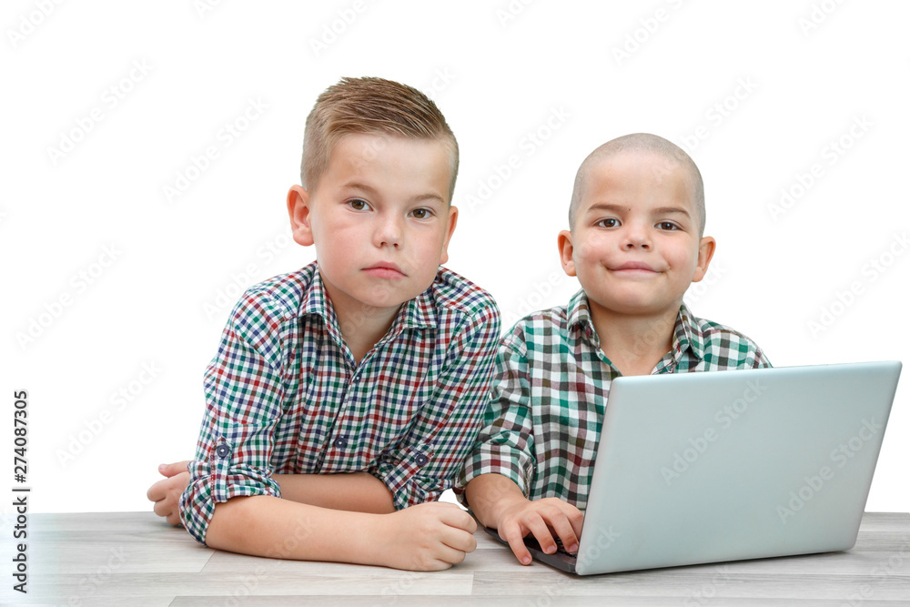 two Caucasian boys ,brothers on a white isolated background. one teaches the other to use a laptop. two Caucasian boys ,brothers on a white isolated background. one teaches the other to use a laptop.