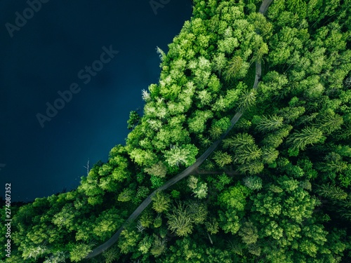 Aerial top view of country road in green summer forest and blue lake. Rural landscape in Finland. © nblxer
