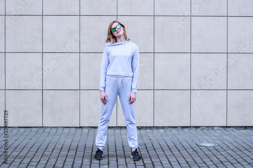 The girl is blonde in a gray sports suit. Street clothing. Sport. Advertising. Fashion and style. Trends. Mockup. Copyspace