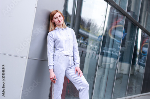 The girl is blonde in a gray sports suit. Street clothing. Sport. Advertising. Fashion and style. Trends. Mockup. Copyspace