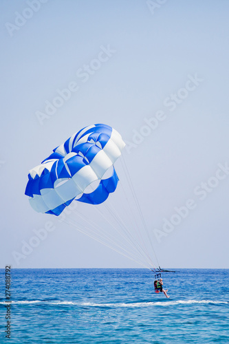 Couple of tourists flies on a blue and white parachute