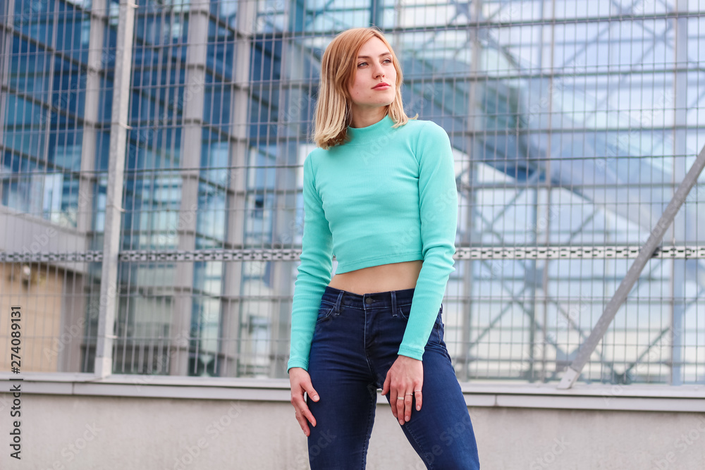 The girl is blonde in a blue croptop. Street clothing. Sport. Advertising. Fashion and style. Copyspace. Mockup