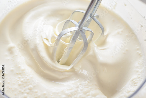 Obraz na plátne Whipping cream with a mixer. Bubbles on cream