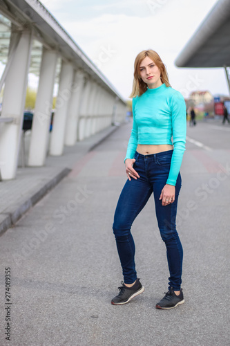 The girl is blonde in a blue croptop. Street clothing. Sport. Advertising. Fashion and style. Copyspace. Mockup © Yaroslav