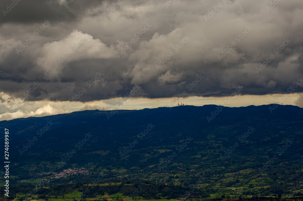 Multiple exposure of an overcasted sky over the central Andean mountains of Colombia, with the farmlands and a typical town of the region.