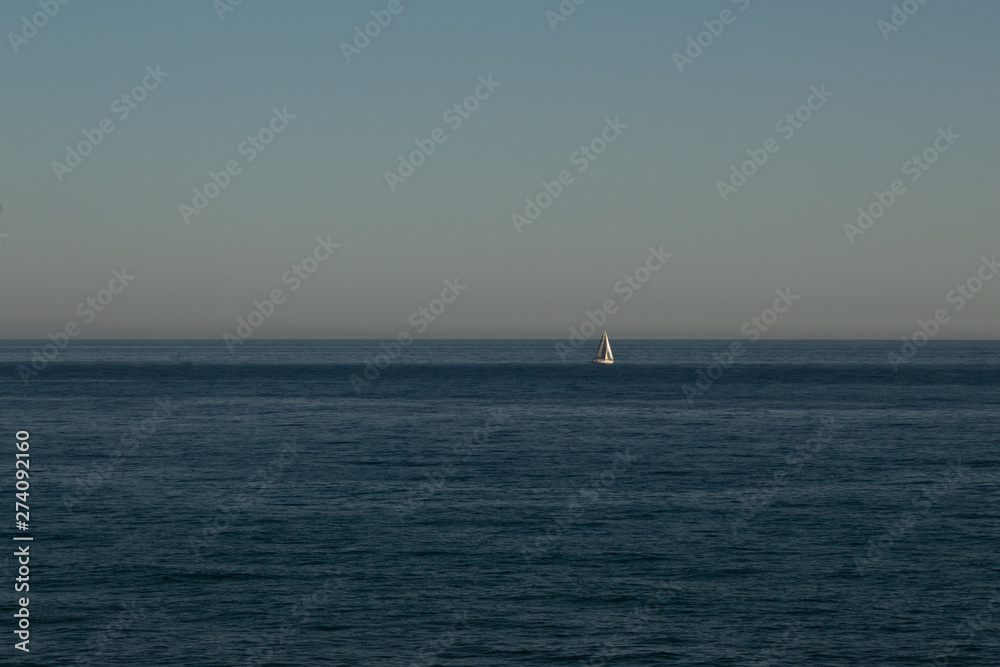Sailing boat in the distance to the sea in the evening Sailing boat in the distance to the sea in the evening