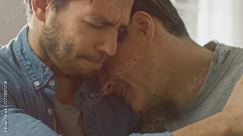 Sad Queer Drama Concept. Close-up Shot of a Unhappy and Depressed Boyfriend. His Gay Friend is Comforting Him, Holding His Hands. Miserable Man Puts His Head on a Shoulder and Cries.