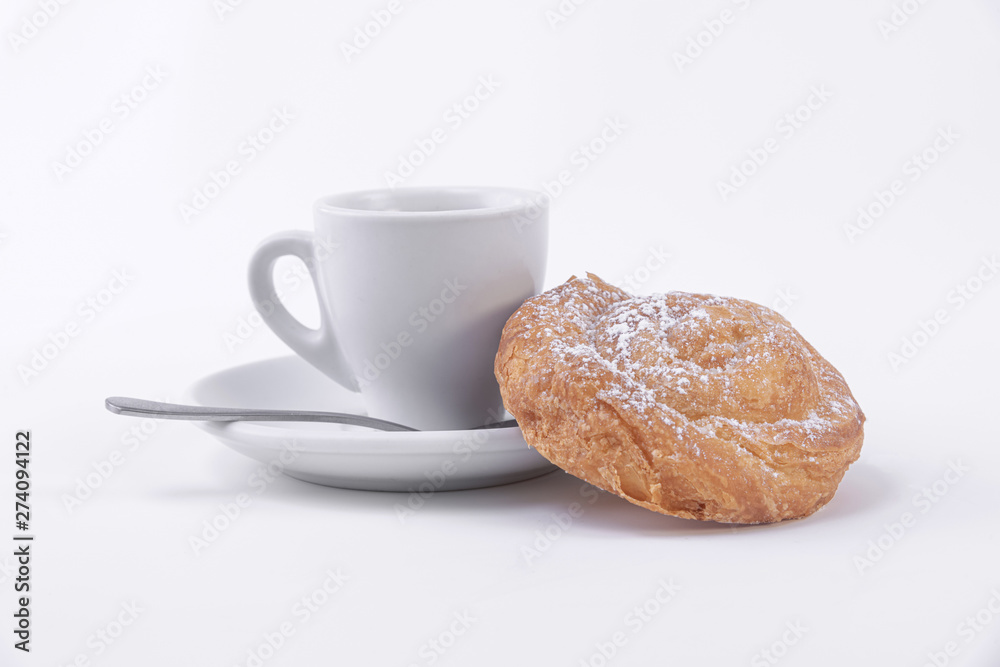 A cup of hot coffee and a roll of puff pastry with powdered sugar on top A cup of hot coffee and a roll of puff pastry with powdered sugar on top